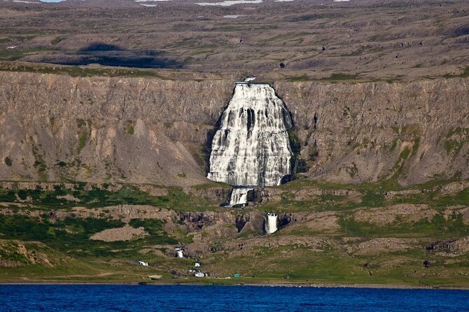 Dynjandi seen from across the fjord, small against the cliff wall behind it