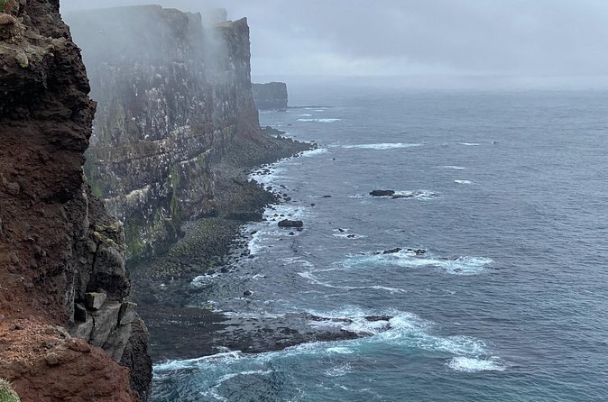 Sea cliffs dropping straight into the water under low Westfjords cloud